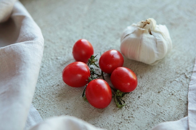 Tomates Cherry y Ajo sobre superficie de hormigón con lino.