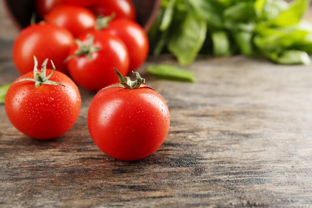 Tomates cherry con albahaca en la mesa de madera de cerca