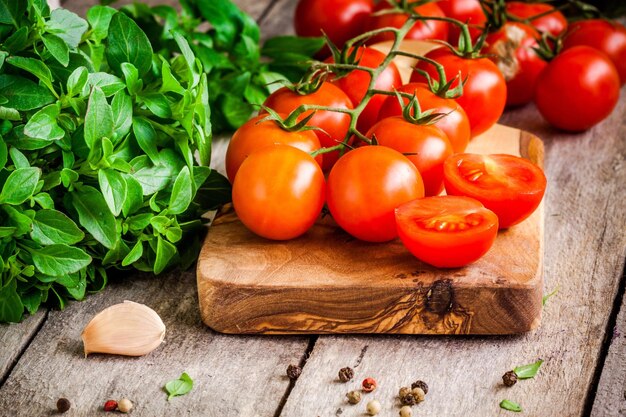 Tomates cherry albahaca orgánica fresca con ajo y pimientos en tabla de cortar de oliva