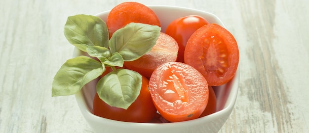 Foto tomates cherry con albahaca en un tazón nutrición saludable fondo de madera vieja