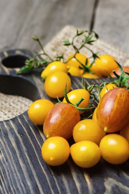 Tomates cherry amarillos y rojos sobre tabla para cortar madera.