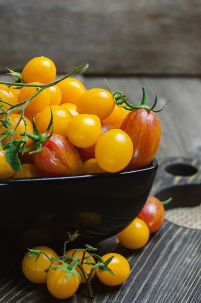 Tomates cherry amarillos y rojos en un tazón negro.