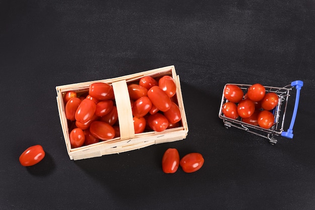 Tomates cherry en una cesta de mimbre y vista superior del carrito de compras