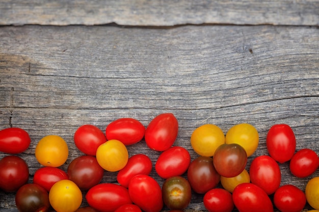 Tomates cherry coloridos sobre superficie de madera con copyspace