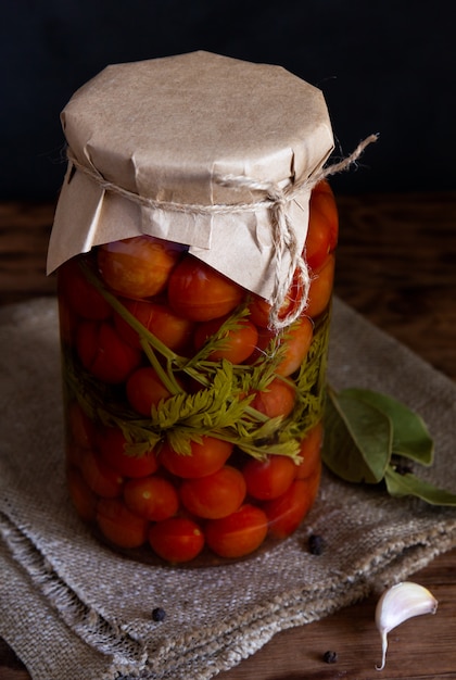 Tomates cherry enlatados en un frasco sobre una mesa de madera