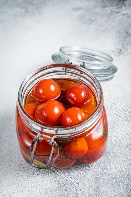 Tomates cherry en escabeche en un frasco de vidrio. Fondo blanco. Vista superior.