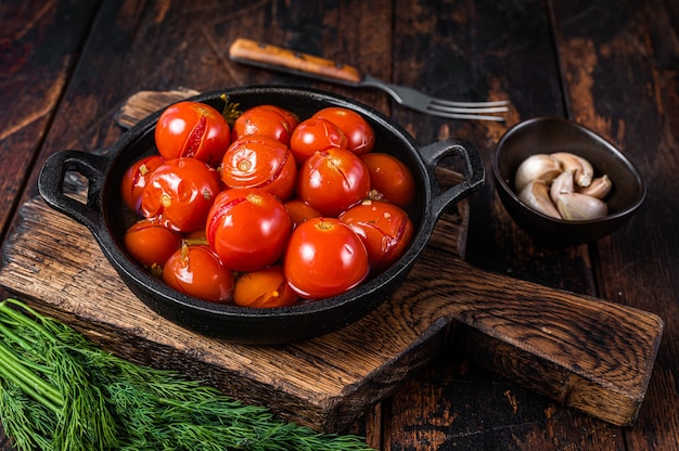 Tomates cherry en escabeche salados en una sartén con hierbas y eneldo