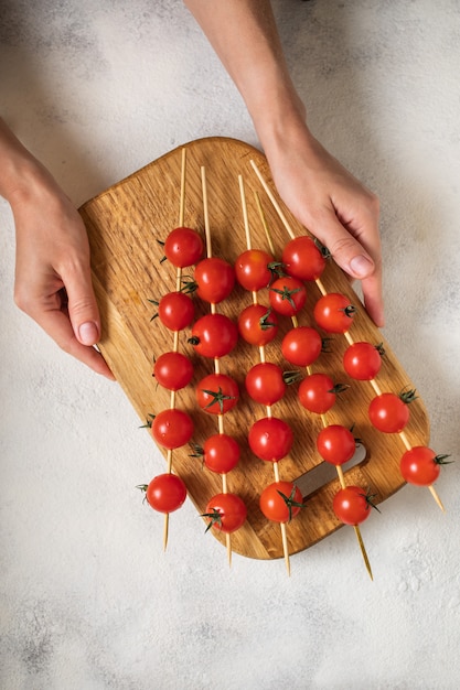 Tomates cherry en espadas sosteniendo con las manos