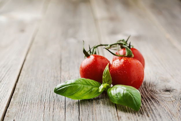 Tomates cherry frescos, hojas de albahaca, queso mozzarella y aceite de oliva en la superficie de madera vieja. Ingredientes de la ensalada caprese