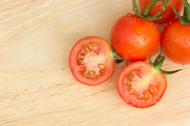 Tomates cherry frescos y maduros con la gota en la tabla de cortar.