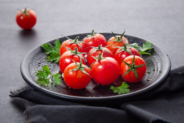 Tomates cherry frescos en plato redondo negro