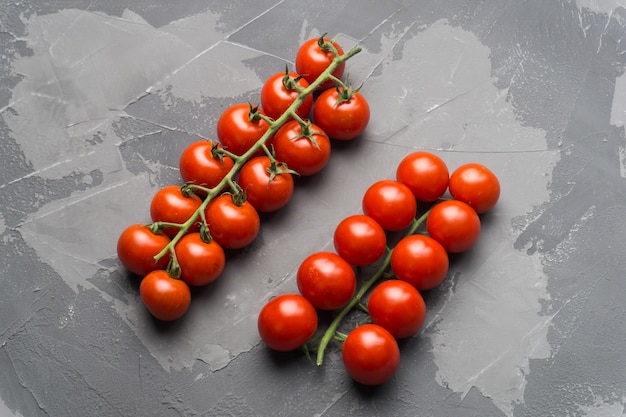 Tomates cherry frescos en una rama sobre un fondo de hormigón negro.