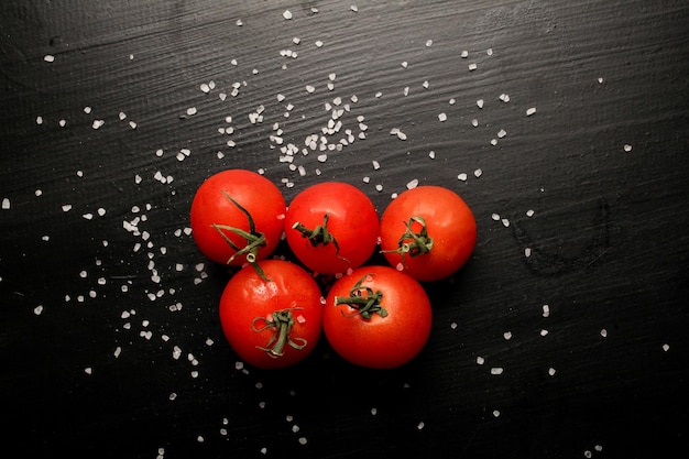 Tomates cherry frescos sobre un fondo negro con especias Vista superior con espacio de copia