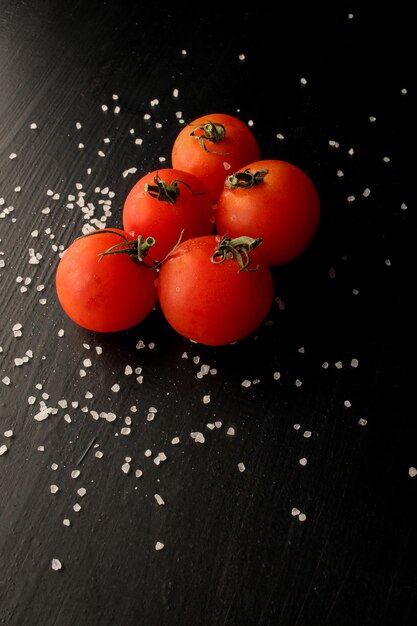 Tomates cherry frescos sobre un fondo negro con especias Vista superior con espacio de copia