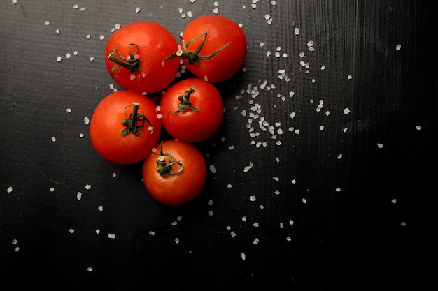Tomates cherry frescos sobre un fondo negro con especias Vista superior con espacio de copia