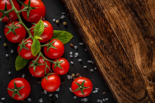 Tomates cherry frescos sobre un fondo negro con especias