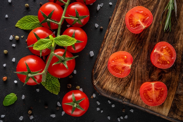 Tomates cherry frescos sobre un fondo negro con especias