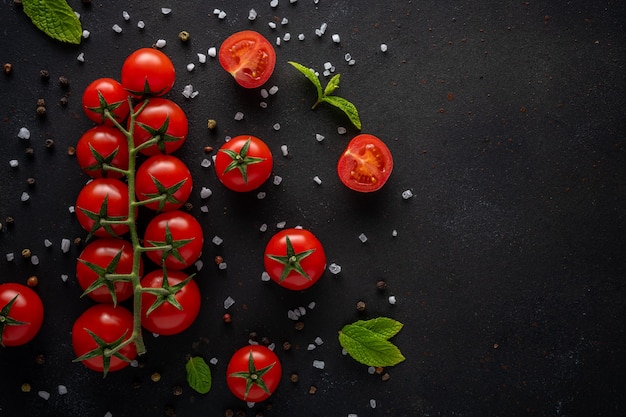 Tomates cherry frescos sobre un fondo negro con especias.