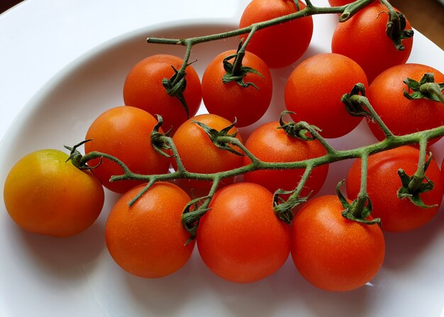 Tomates Cherry maduros en una placa blanca.