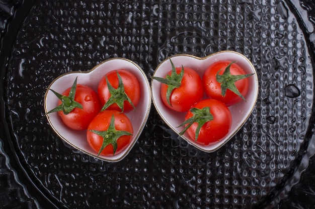 Tomates cherry maduros rojos tomates en un tazón en forma de corazón
