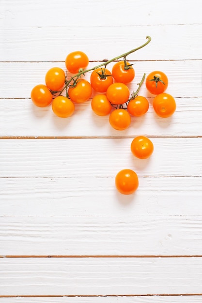 Tomates cherry naranja sobre fondo blanco de madera