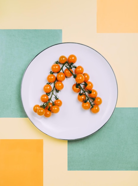 Tomates cherry naranjas en ramas en un plato blanco