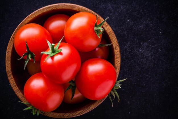 Tomates cherry orgánicos frescos en un tazón de cerca sobre un fondo oscuro