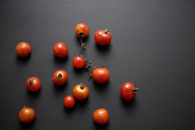 Los tomates cherry planas yacían sobre fondo abstracto de textura grunge negro con vista superior