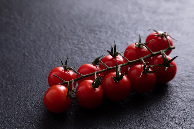 Tomates cherry en una rama sobre un fondo oscuro