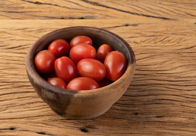 Tomates cherry en un recipiente sobre la mesa de madera.