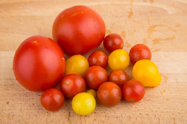 Tomates cherry rojos y amarillos en una tabla para cortar madera