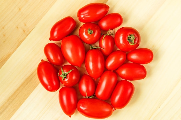 Tomates cherry rojos ciruela forma madura sobre fondo de mesa de madera. Productos locales del mercado de temporada.