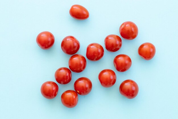 Tomates cherry rojos frescos sobre fondo azul.