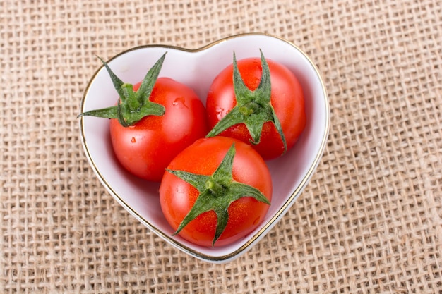 Tomates cherry rojos en un recipiente en forma de corazón