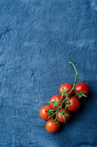 Tomates cherry sobre tela azul encima de la vista con mucho espacio para copiar