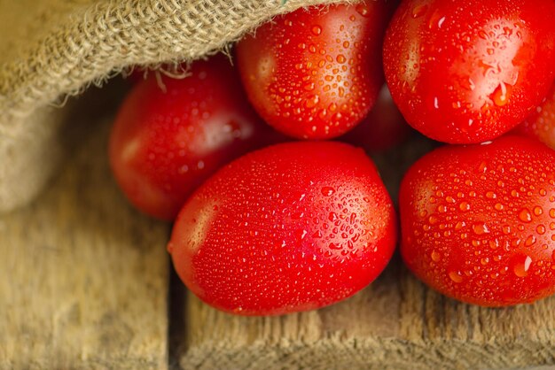 Tomates de ciruela largos en la mesa de madera Montón de tomates frescos