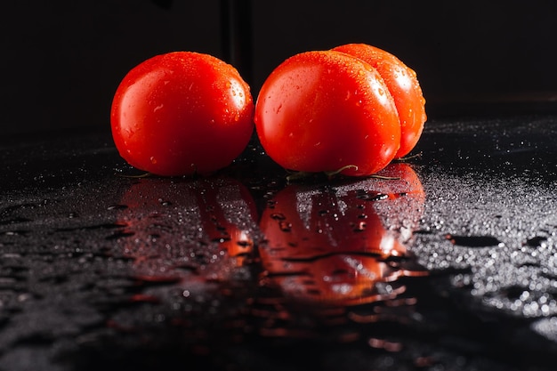 Tomates com gotas de água no fundo preto