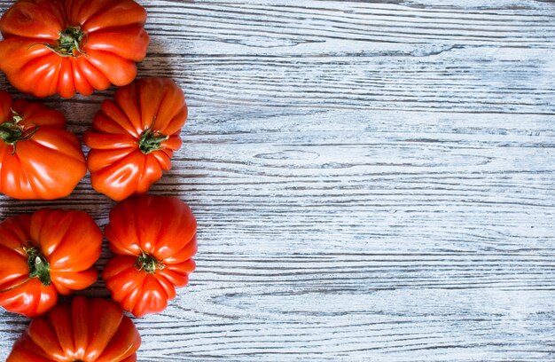 Tomates de corazón de buey, sobre fondo de madera rústica, espacio libre para texto.