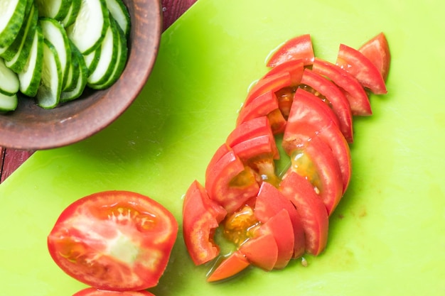 Foto los tomates se cortan en una tabla de cortar preparación para la producción de ensalada de verduras