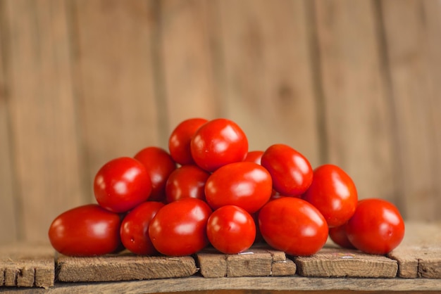 Tomates de ameixa frescos da agricultura de verão grupo de tomates em pasta tomate longo fresco em uma mesa de madeira