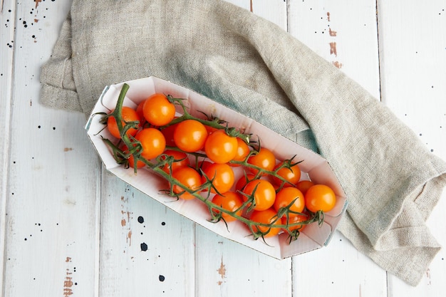 Tomates de cereja amarelos frescos no fundo branco de madeira