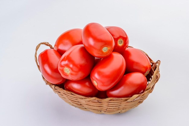 Tomates dentro de la cesta de paja aislado sobre fondo blanco.