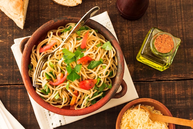 Foto tomates e coentros sobre o macarrão espaguete em barro