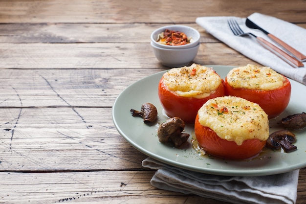 Tomates enteros al horno rellenos de champiñones y queso con condimentos. Copia espacio