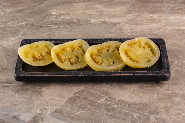 Tomates en escabeche colocados sobre una mesa de piedra.