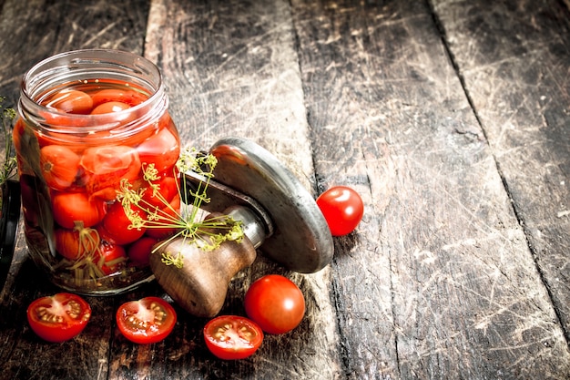 Tomates en escabeche con especias de hierbas y selladora en mesa de madera.