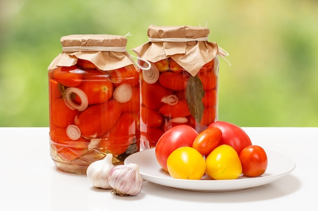 Tomates en escabeche en frascos de vidrio sobre fondo natural.