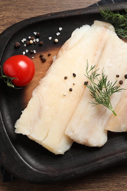 Tomates y especias de eneldo de bacalao crudo en una mesa de madera