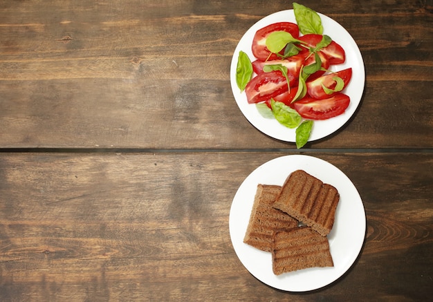 Tomates fatiados com alface. Torrada de pão fresco. Alimentação saudável