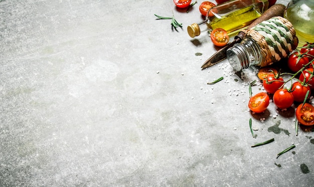 Tomates en el fondo. Tomates frescos, aceite de oliva y especias. Sobre un fondo de piedra.